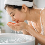 세면대에서 손으로 물을 떠 얼굴에 가져가는 모습으로 표현된 찬물 세안 장면